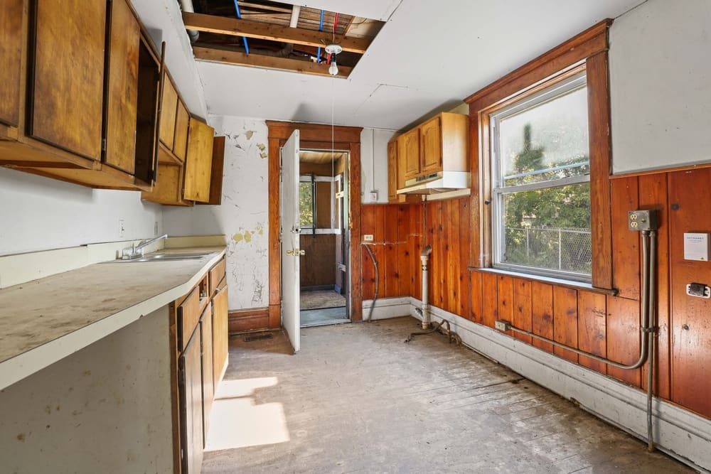 An older kitchen with the ceiling opened up and peeling walls